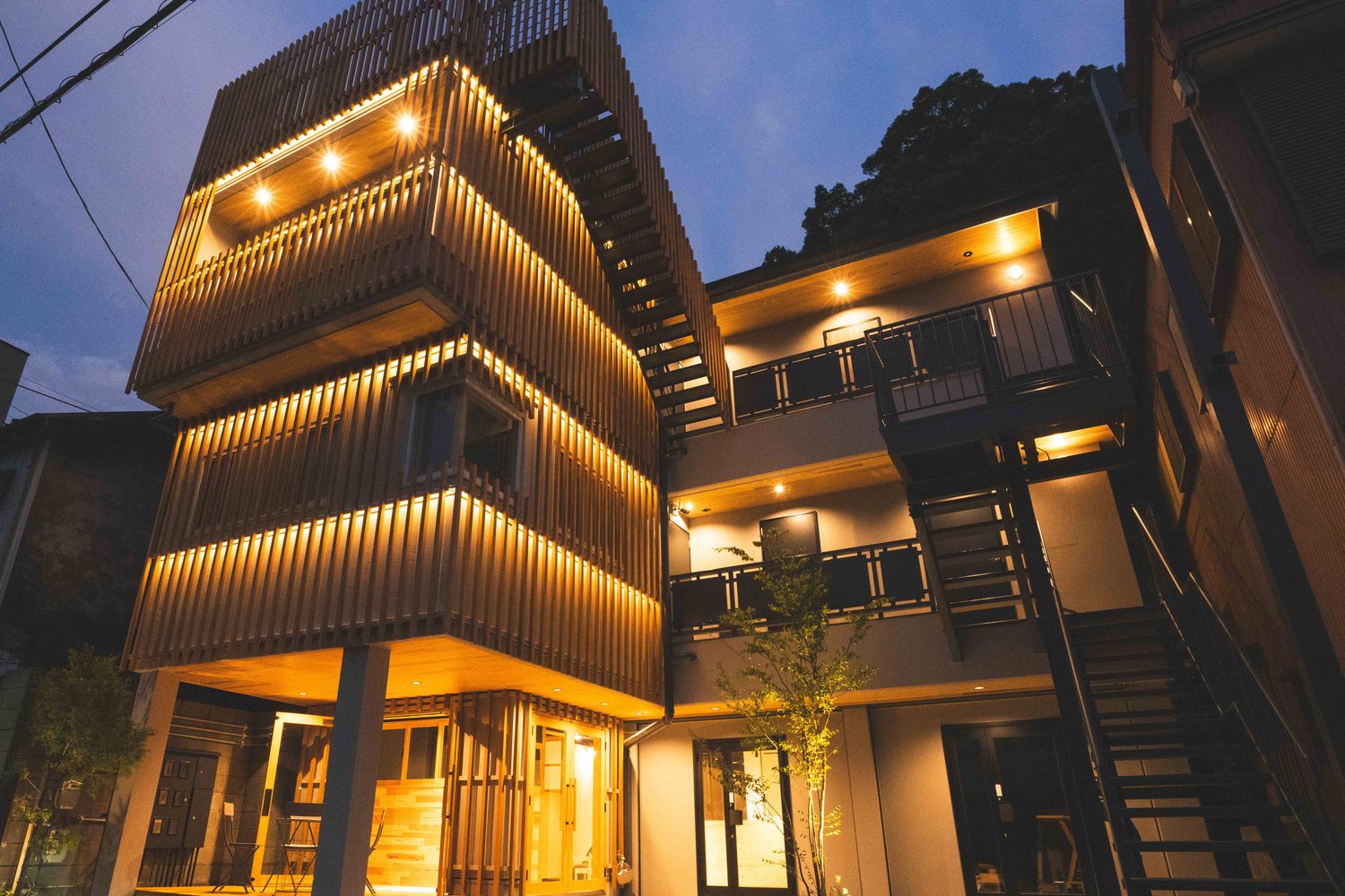 夕暮れに灯りがともる一棟貸しの宿の外観(Hotel Re:Plug)